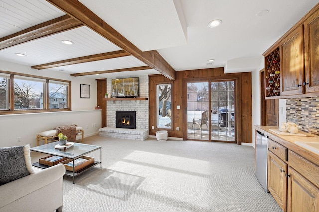 living room with beam ceiling, a fireplace, and light colored carpet