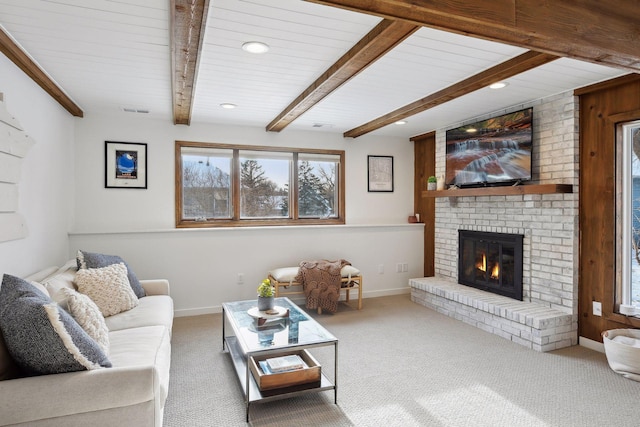 carpeted living room featuring beamed ceiling and a fireplace