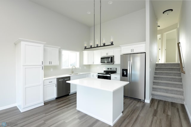 kitchen with sink, a center island, hanging light fixtures, appliances with stainless steel finishes, and white cabinets