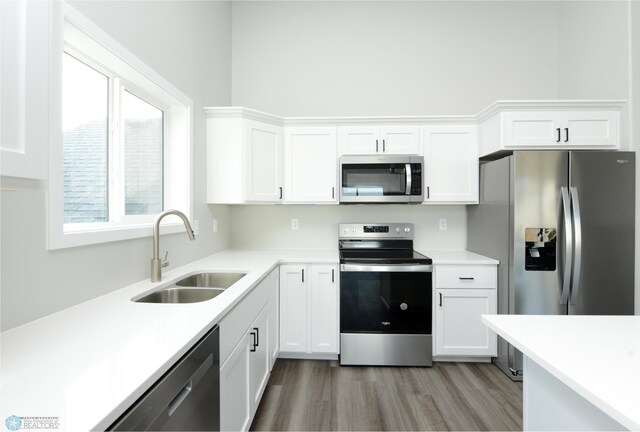 kitchen with stainless steel appliances, hardwood / wood-style flooring, sink, and white cabinets