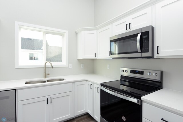 kitchen with appliances with stainless steel finishes, sink, and white cabinets