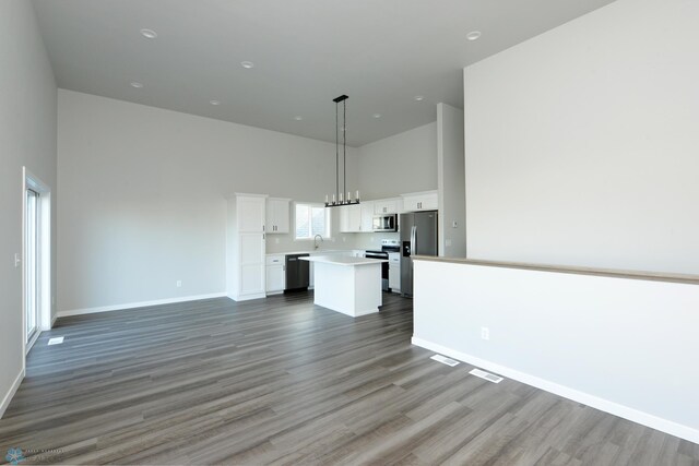 kitchen with hanging light fixtures, a kitchen island, appliances with stainless steel finishes, and white cabinets