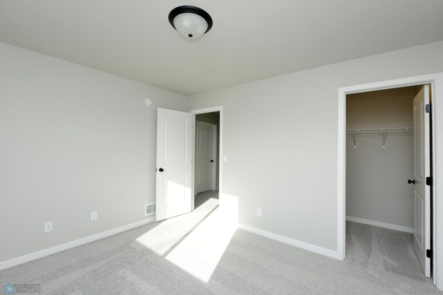 unfurnished bedroom featuring light colored carpet, a spacious closet, and a closet