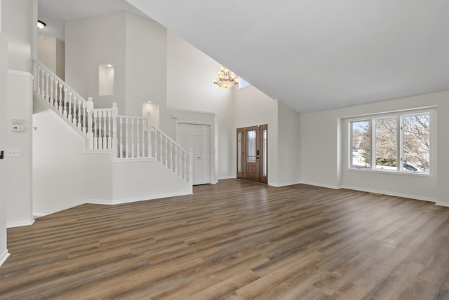 unfurnished living room featuring dark hardwood / wood-style floors, high vaulted ceiling, and a notable chandelier