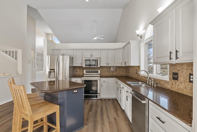 kitchen with sink, a breakfast bar, stainless steel appliances, a center island, and white cabinets