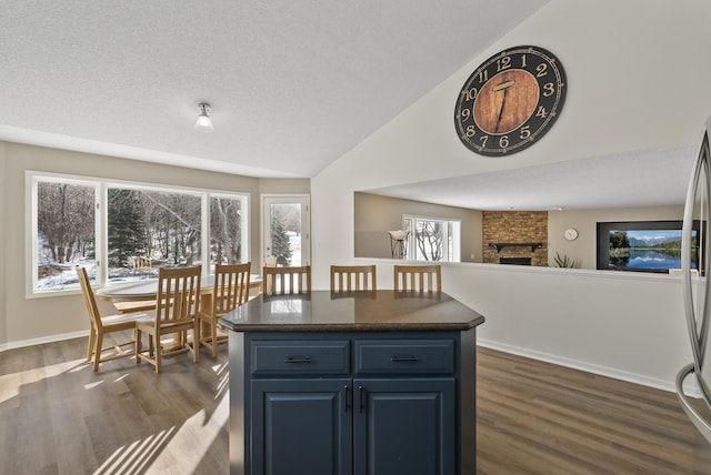 kitchen with dark hardwood / wood-style flooring, vaulted ceiling, a center island, and blue cabinets