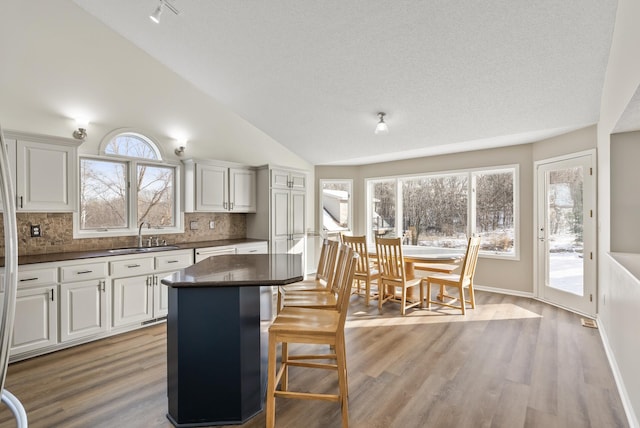 kitchen with a kitchen island, sink, white cabinets, and a kitchen bar