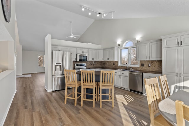 kitchen with a breakfast bar area, a kitchen island, ceiling fan, stainless steel appliances, and decorative backsplash