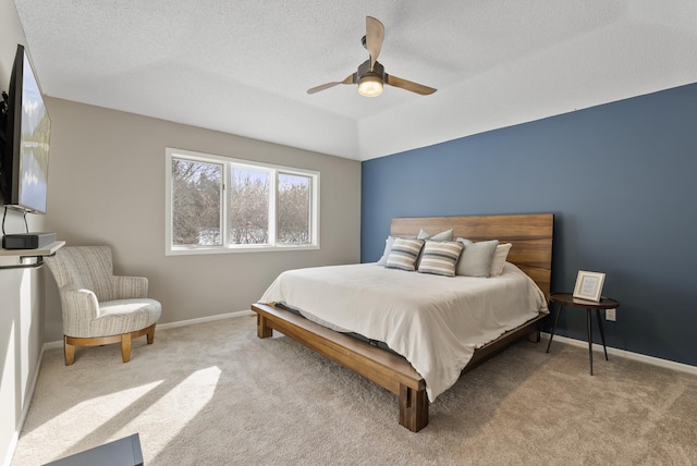 bedroom with ceiling fan, light colored carpet, and a textured ceiling