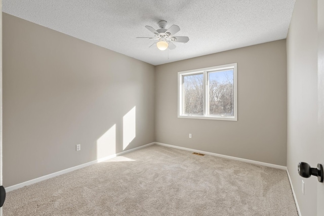 carpeted empty room with ceiling fan and a textured ceiling