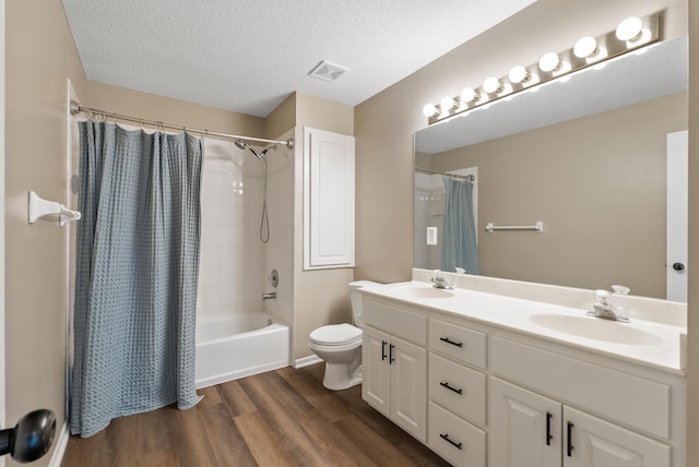 full bathroom with toilet, a textured ceiling, vanity, shower / bath combo with shower curtain, and hardwood / wood-style floors