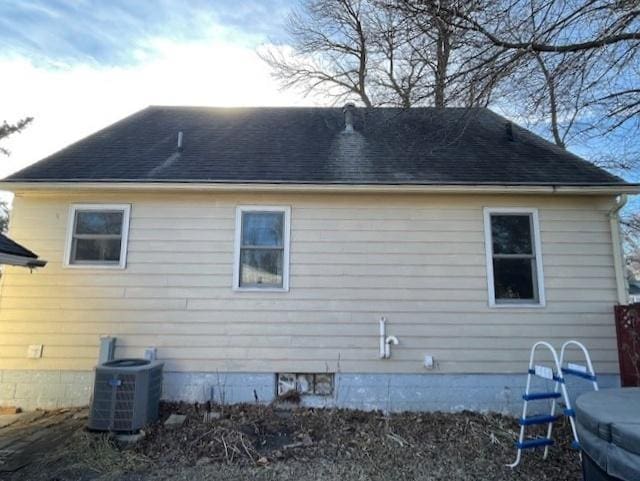 rear view of property with a shingled roof and central air condition unit