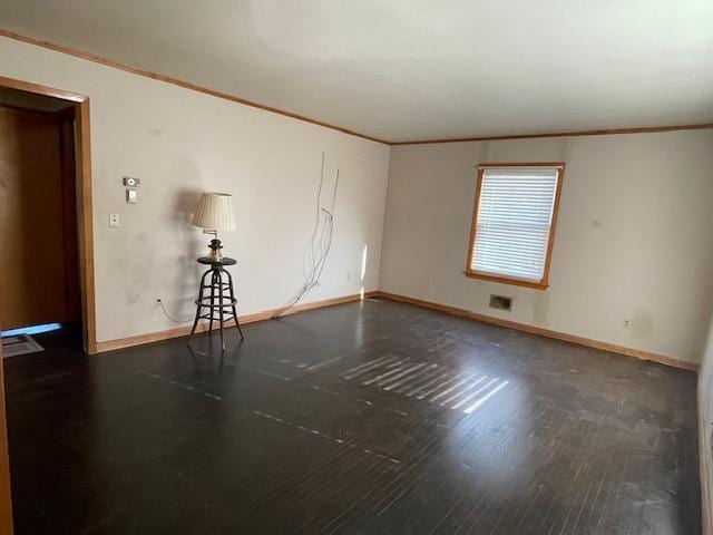 unfurnished room featuring baseboards, wood finished floors, and crown molding