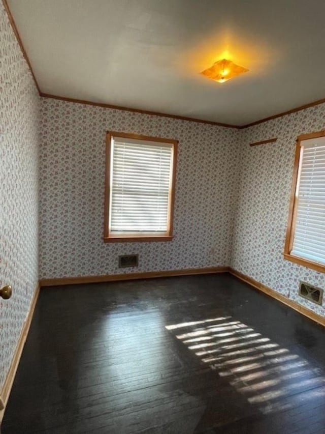 empty room with wallpapered walls, ornamental molding, and hardwood / wood-style floors