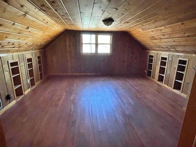 additional living space featuring wooden walls, built in features, wood ceiling, wood finished floors, and vaulted ceiling