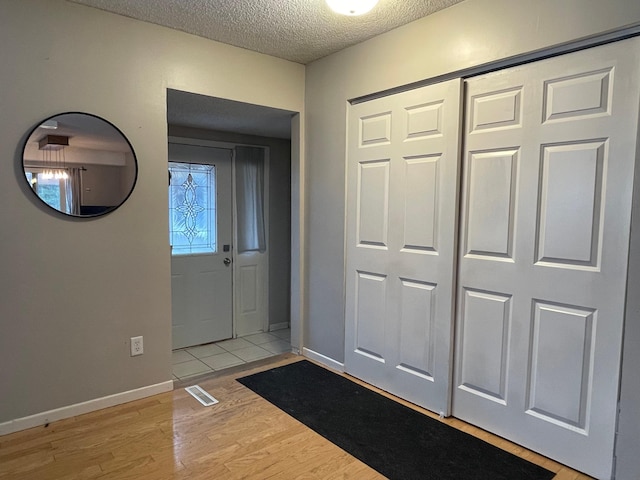 foyer entrance featuring a textured ceiling and light wood-type flooring