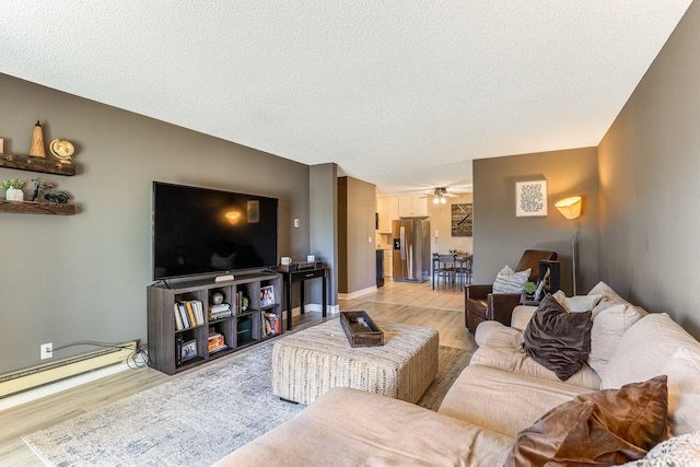 living room featuring a baseboard heating unit, light hardwood / wood-style flooring, a textured ceiling, and ceiling fan