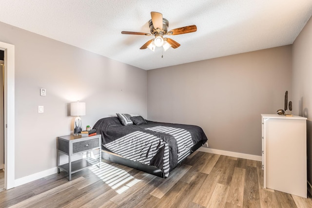 bedroom featuring ceiling fan, hardwood / wood-style floors, and a textured ceiling