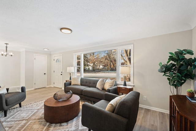 living room featuring an inviting chandelier, light hardwood / wood-style flooring, and a textured ceiling