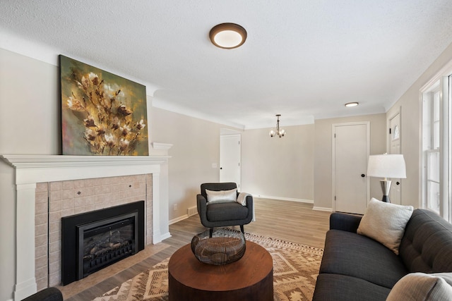 living room featuring a textured ceiling, a fireplace, a chandelier, and wood-type flooring