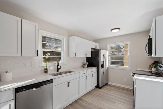 kitchen featuring sink, appliances with stainless steel finishes, white cabinetry, light hardwood / wood-style floors, and decorative backsplash