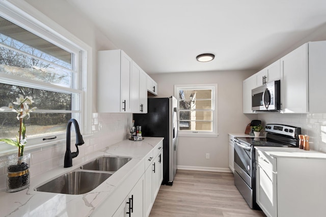 kitchen featuring white cabinetry, sink, light stone counters, and stainless steel appliances