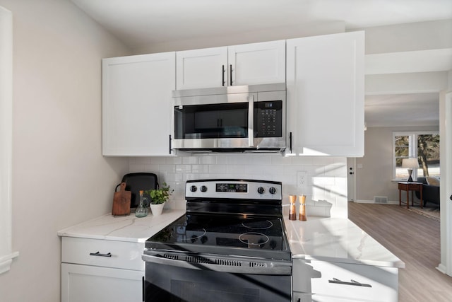 kitchen with light stone countertops, white cabinetry, appliances with stainless steel finishes, and decorative backsplash