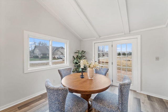 dining area featuring wood-type flooring and vaulted ceiling with beams