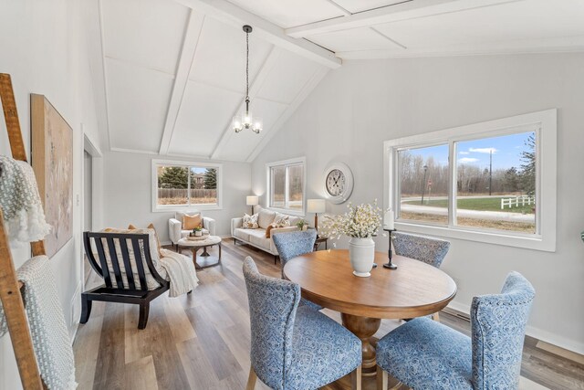 dining room featuring beam ceiling, hardwood / wood-style flooring, high vaulted ceiling, and a chandelier