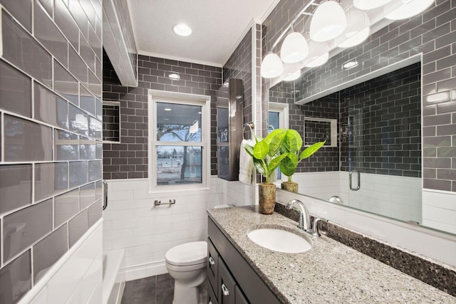 bathroom with tile walls, tile patterned flooring, vanity, a shower with shower door, and toilet