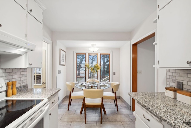 kitchen with decorative backsplash, light stone countertops, white cabinets, and electric stove