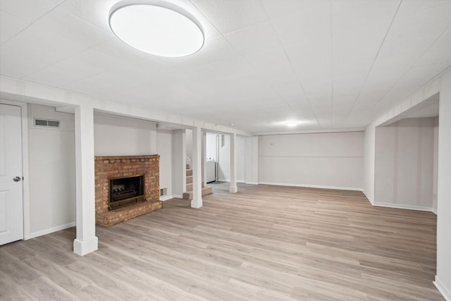 basement featuring a fireplace and light hardwood / wood-style floors