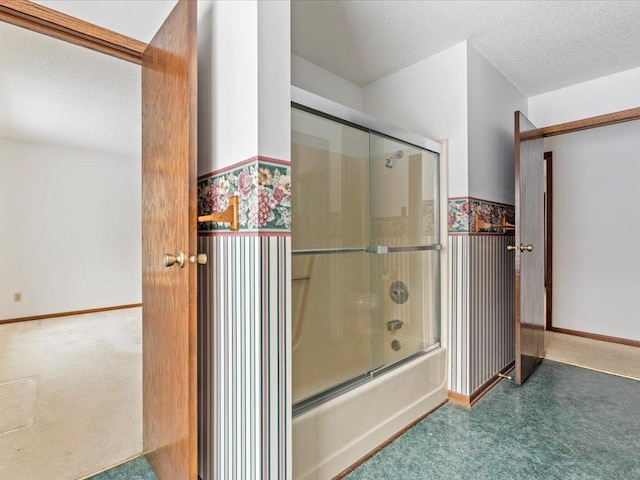 bathroom with combined bath / shower with glass door and a textured ceiling