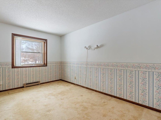 carpeted empty room featuring baseboard heating and a textured ceiling