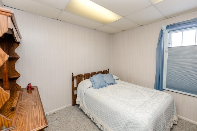 bedroom with a drop ceiling and light colored carpet