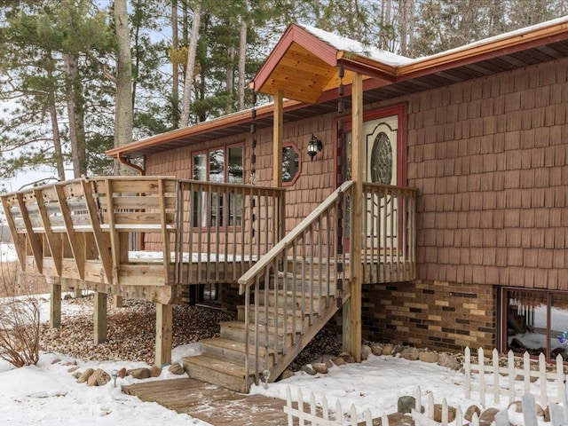 snow covered property entrance with a deck