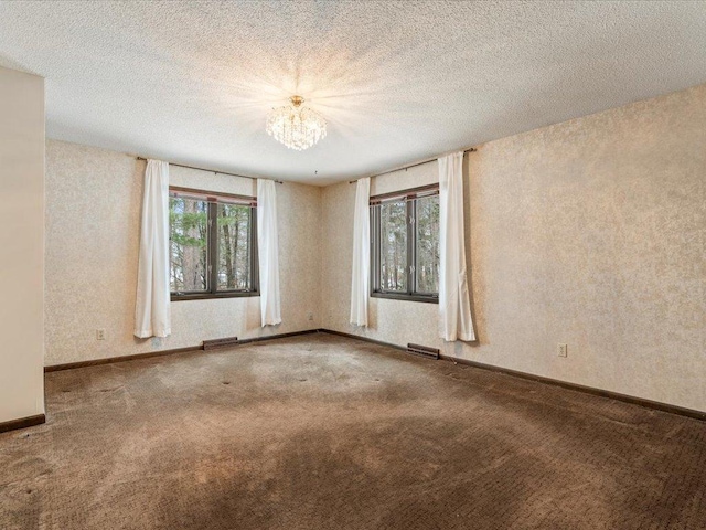 empty room featuring carpet floors, a textured ceiling, and a chandelier