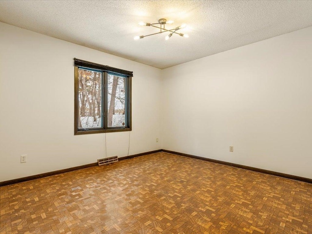 spare room featuring parquet floors, a chandelier, and a textured ceiling