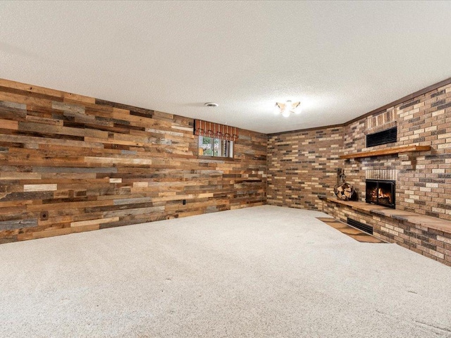 unfurnished living room featuring wood walls, carpet flooring, a brick fireplace, and a textured ceiling