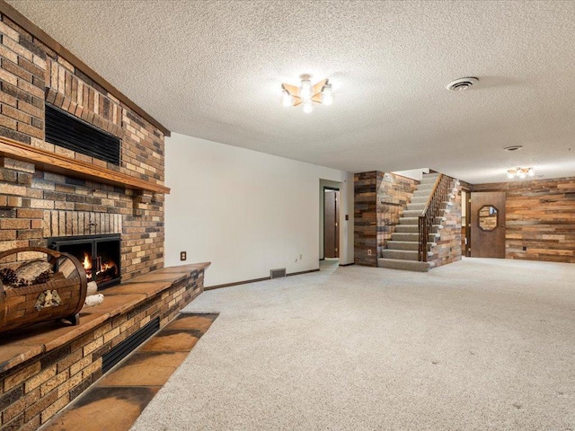 carpeted living room featuring a brick fireplace, a textured ceiling, and wood walls