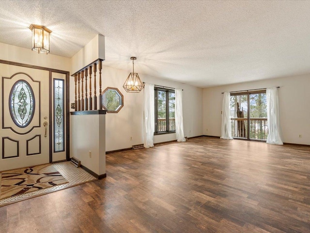 foyer featuring dark hardwood / wood-style floors, a wealth of natural light, a textured ceiling, and a notable chandelier