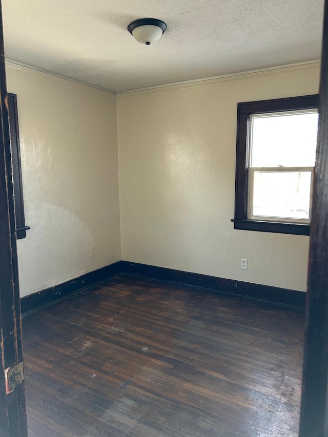 unfurnished room featuring dark wood-type flooring and a textured ceiling