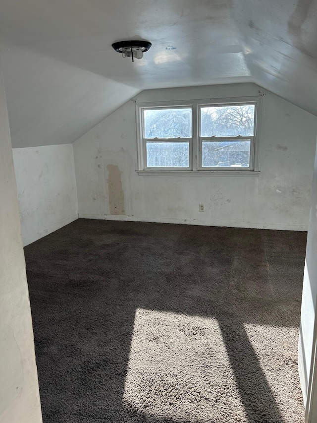 bonus room with dark carpet, plenty of natural light, and vaulted ceiling