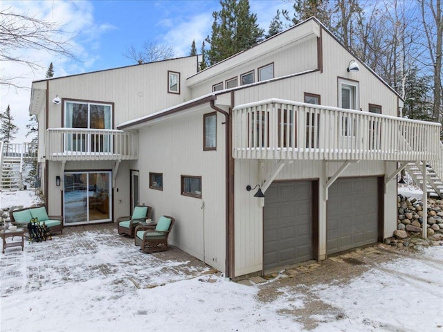 snow covered property featuring a balcony and a garage