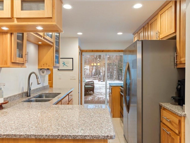 kitchen featuring stainless steel fridge, light stone countertops, sink, and light tile patterned floors