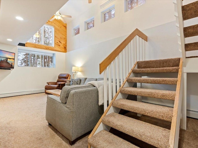 stairs with a high ceiling, a baseboard radiator, carpet flooring, and ceiling fan