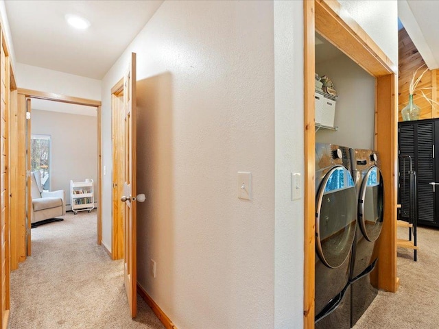 corridor with light carpet and washer and dryer