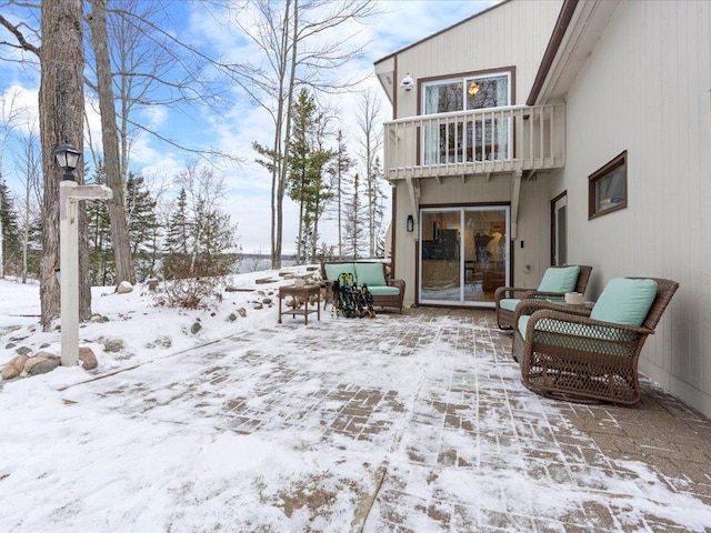 snow covered back of property with a balcony