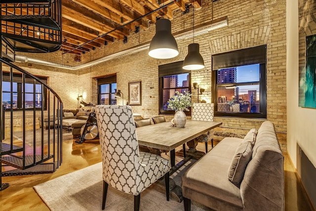 dining space featuring a towering ceiling, concrete flooring, and brick wall