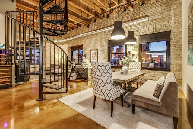 dining space with brick wall, concrete flooring, and a high ceiling